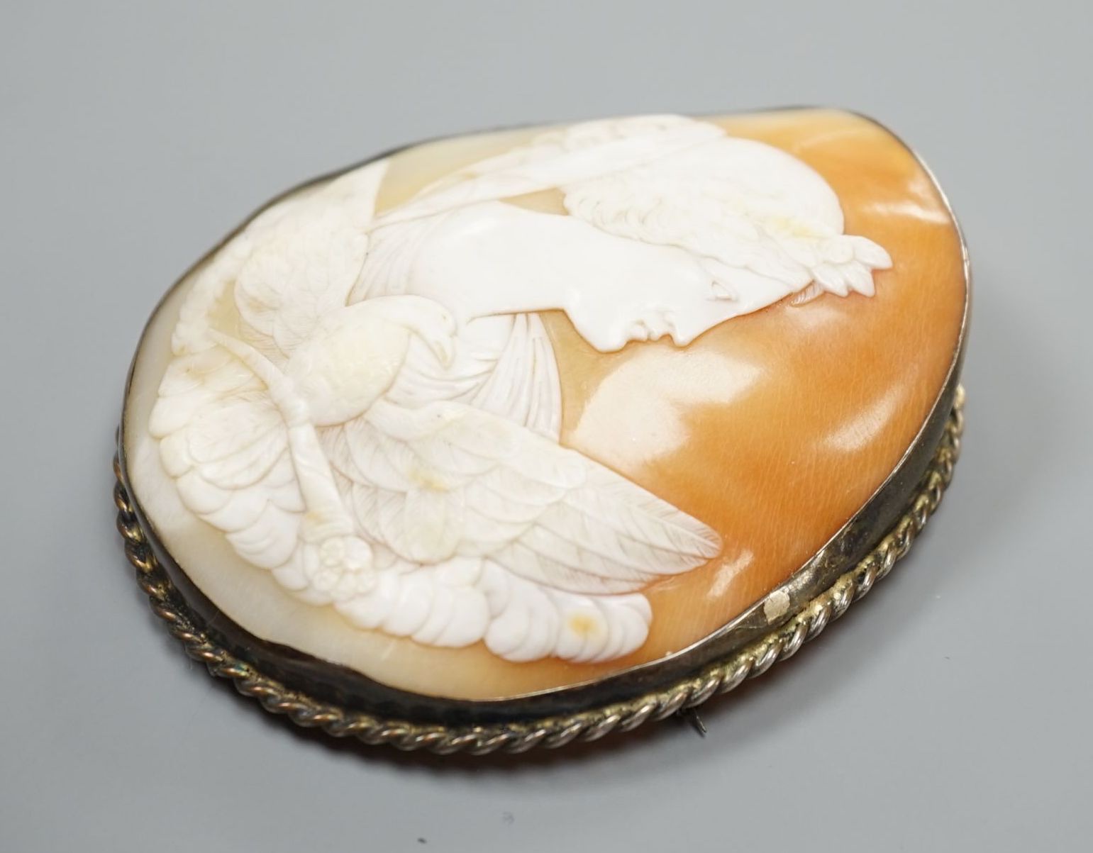 A large white metal mounted oval cameo shell brooch, carved with the Goddess Diana and eagle, 75mm.